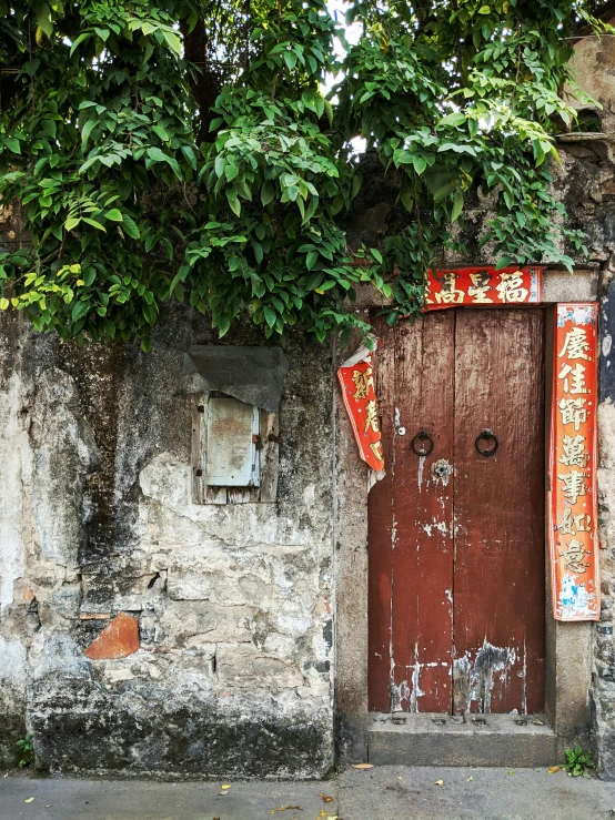 a brick wall has a wood door, with two asian characters hanging on the door