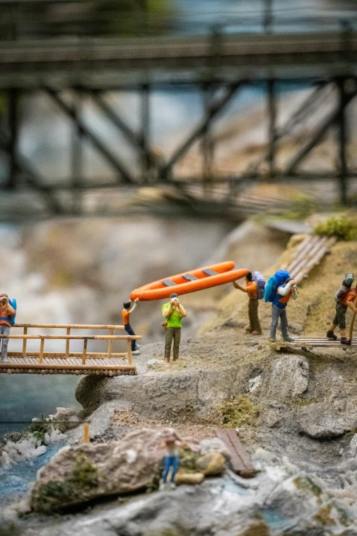 miniature people walk across a bridge over a body of water