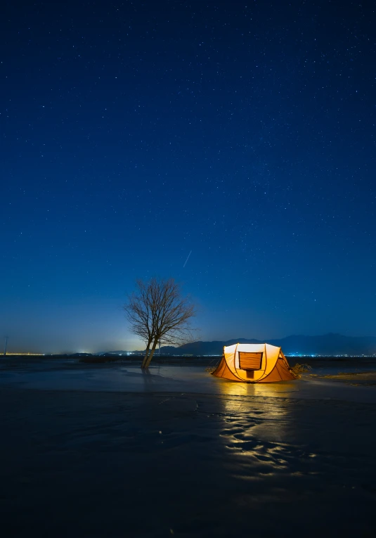 a camper sits in the dark on the lake at night