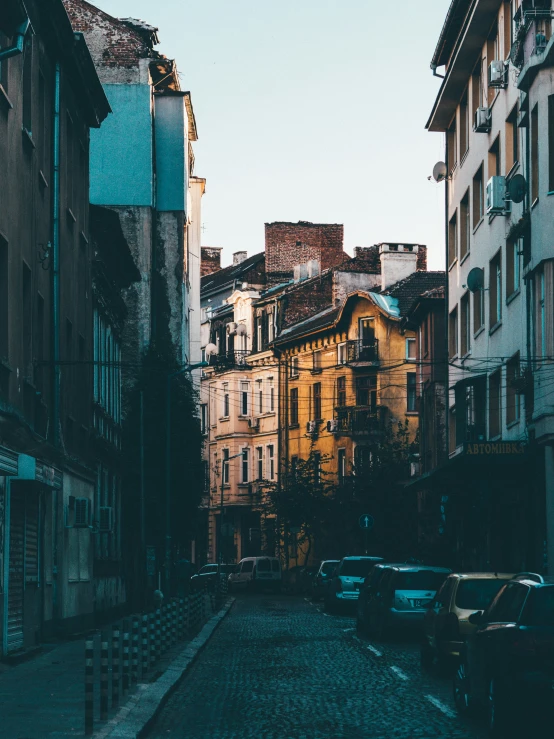 a street full of parked cars next to tall buildings