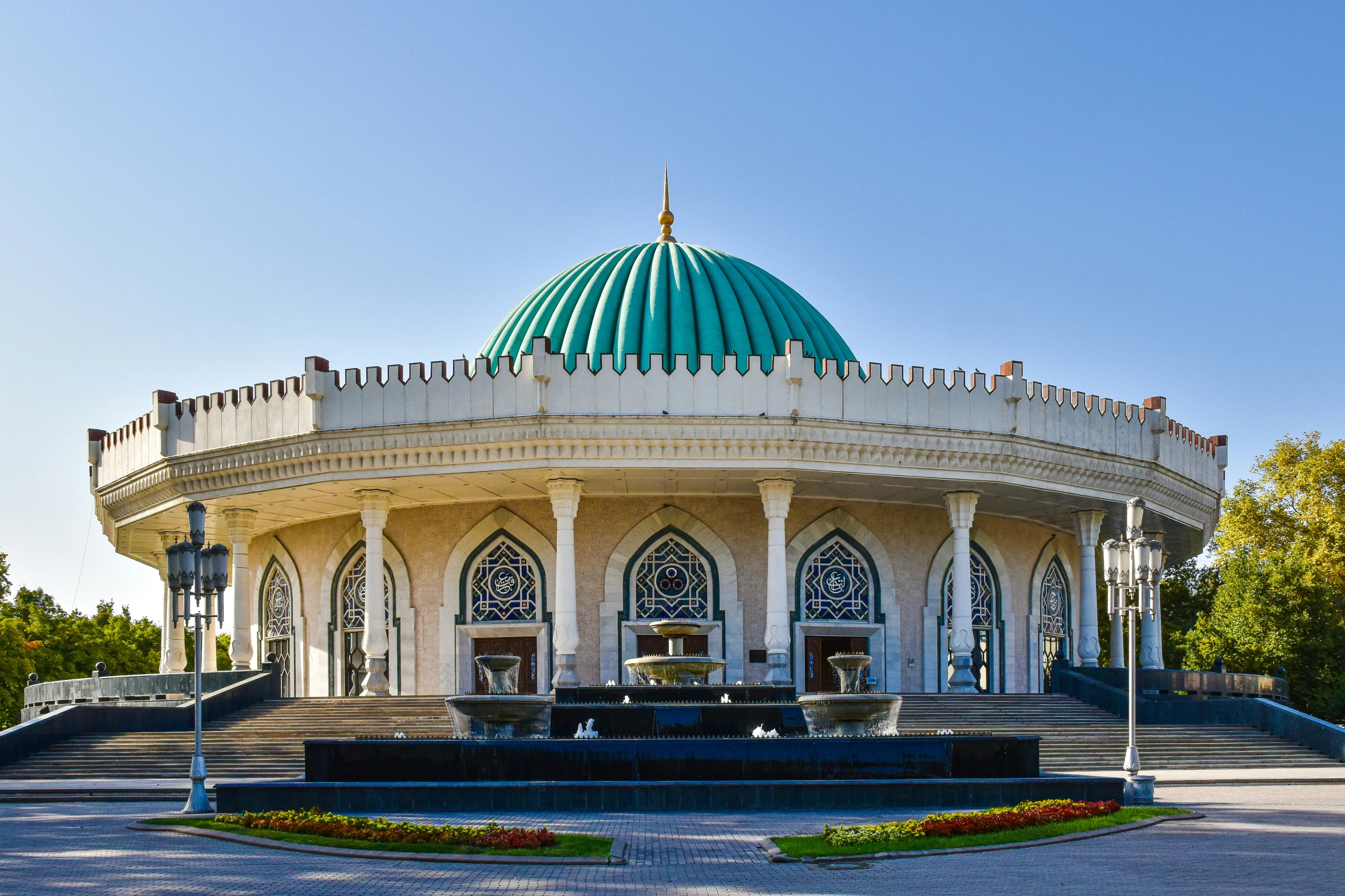 a beautifully designed mosque in a park surrounded by trees