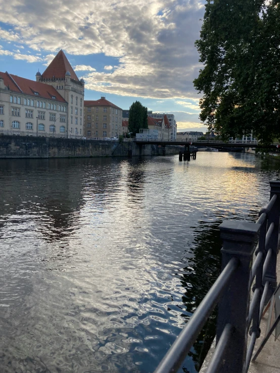 buildings along the riverbank with clouds reflecting in it