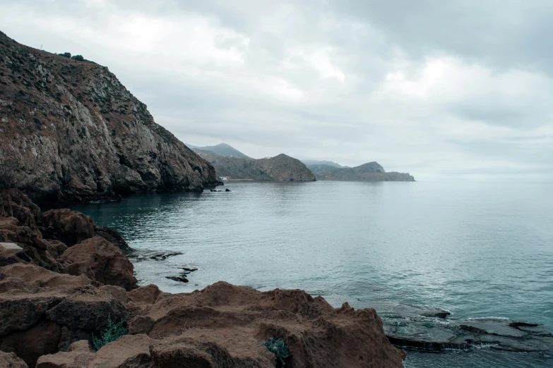 water and rocky shore with mountain in background