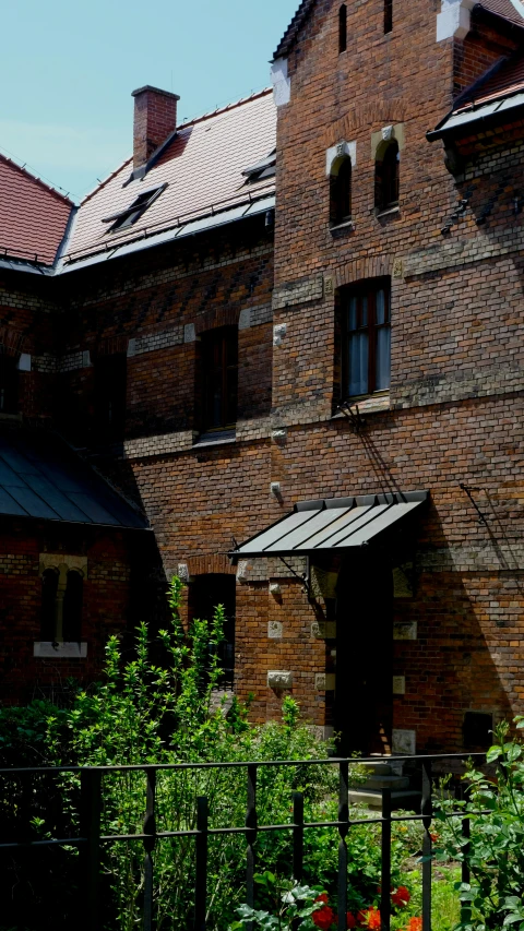 a tall brick building sitting in the middle of a lush green field