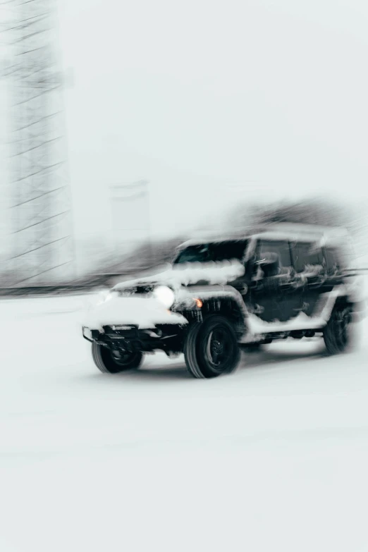 this black and white jeep is driving in the snow