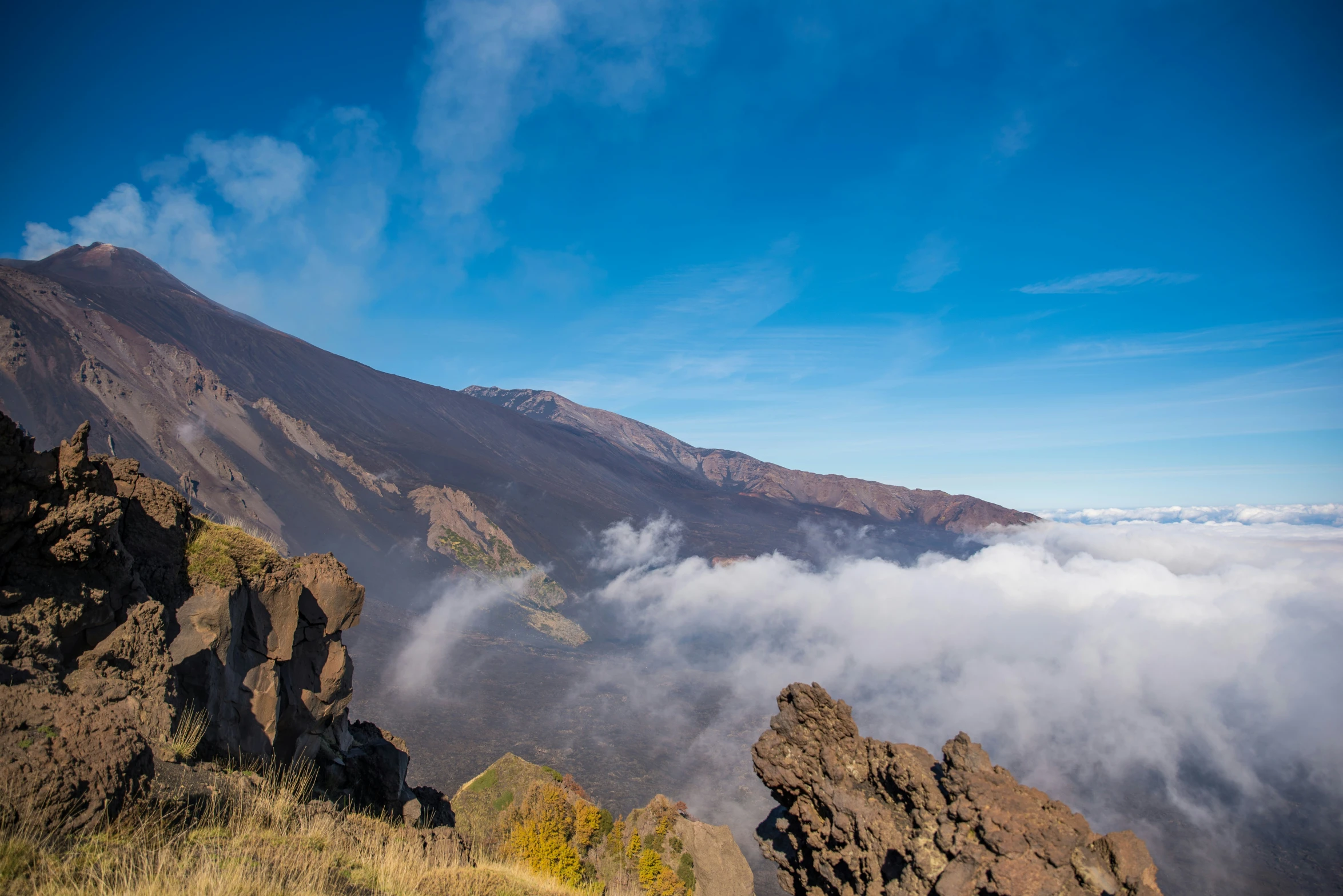 a view looking down at a rocky mountain in a cloudgy sky