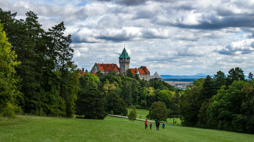 people walking down a green hill towards a large building