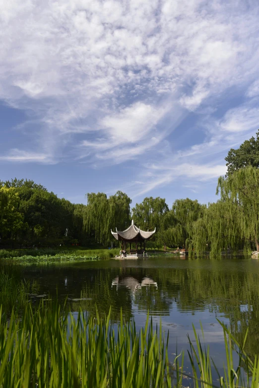 a body of water in front of trees with a white structure in the middle