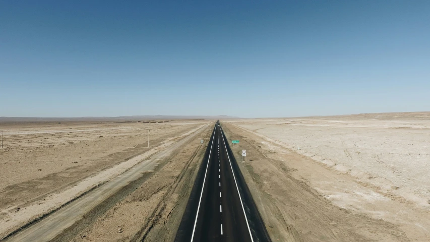 the road through the desert has a sign next to it