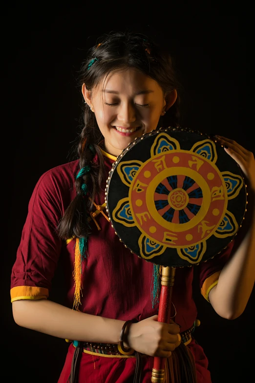 a woman wearing an ethnic style outfit holds up a decorative item