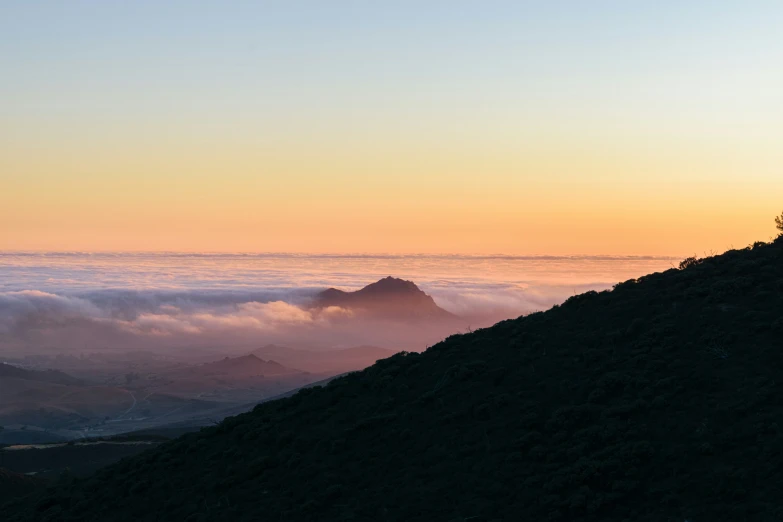 a person standing on top of a mountain with clouds