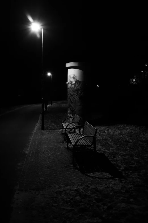 some benches near a light post with a graffiti covered wall