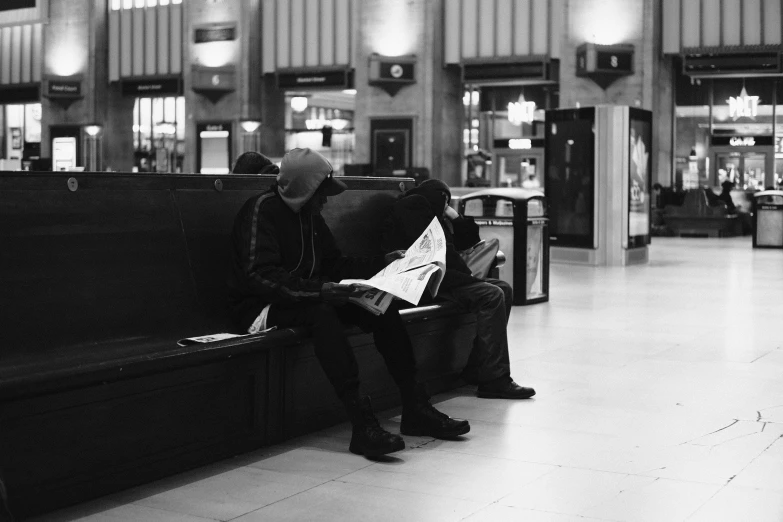 two people are sitting on the bench in the train station