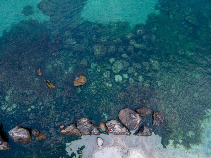 an aerial view of rocks in a body of water