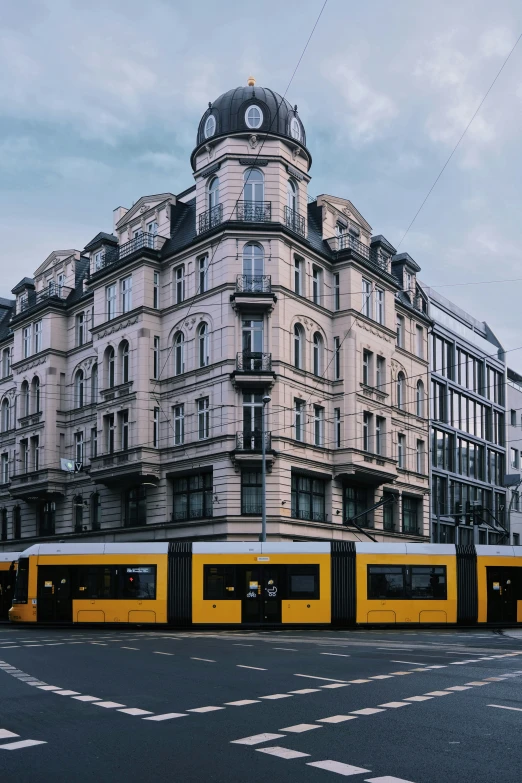 several yellow trains at a train station by a very tall building