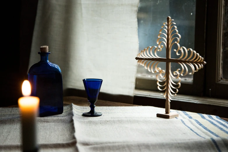 a small wooden cross next to a glass candle