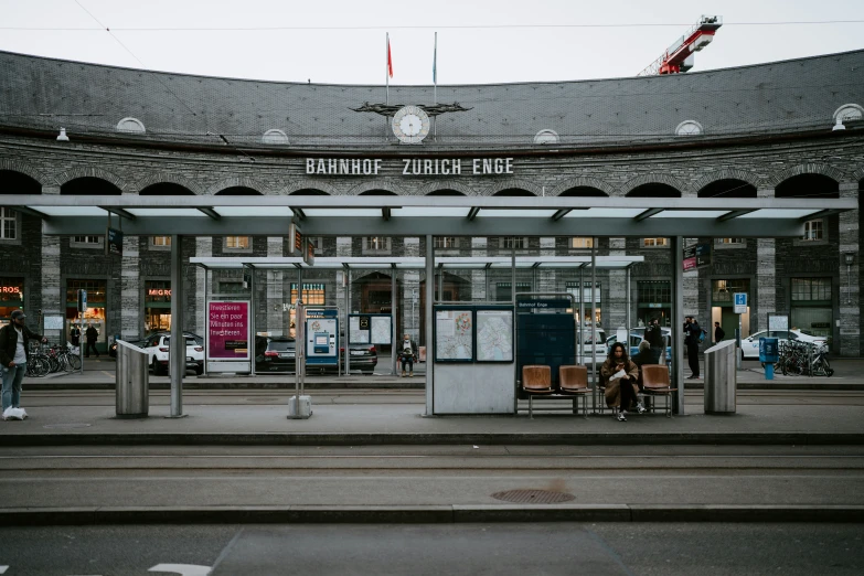 people sitting outside a train station on the street