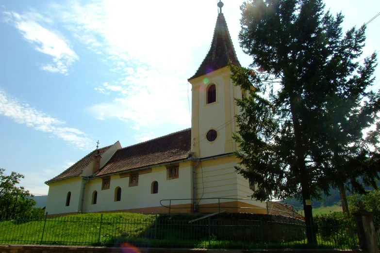 the sun shines on a church with green trees