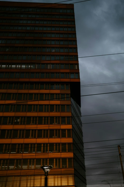 a very tall building next to wires under a cloudy sky