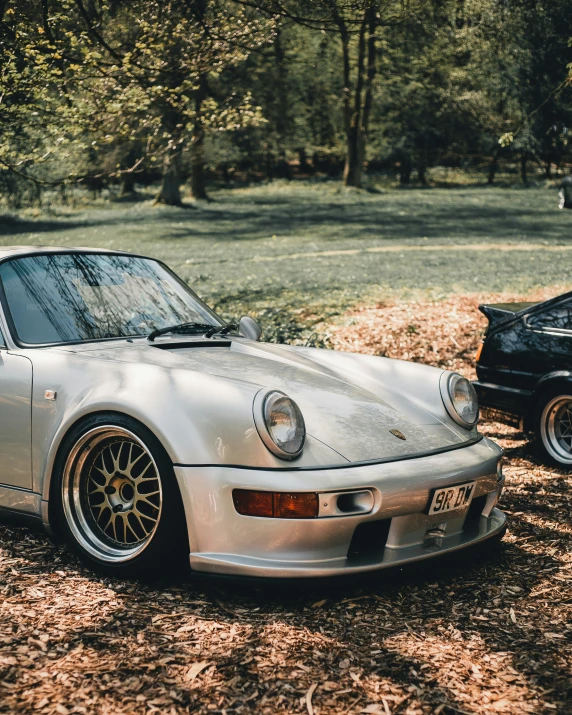 two porsche cars are parked near one another