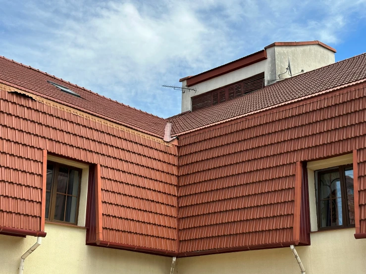 an orange painted building has windows and a red roof