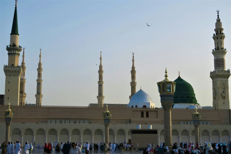 a large crowd gathers in front of a mosque