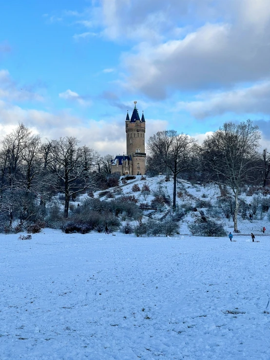 a clock tower towering over the snow covered park