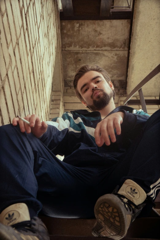 a man sitting down in front of a brick wall