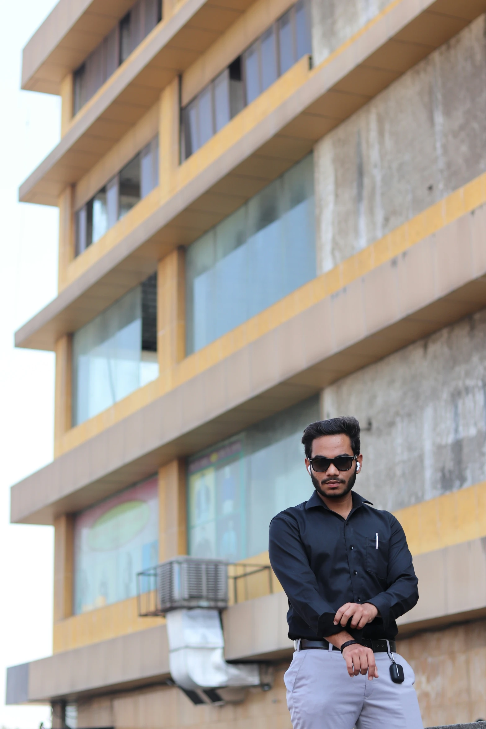 an indian man leaning against his hand with a black shirt