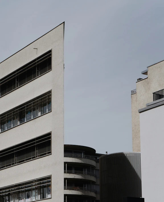 a gray building with several windows next to two white buildings