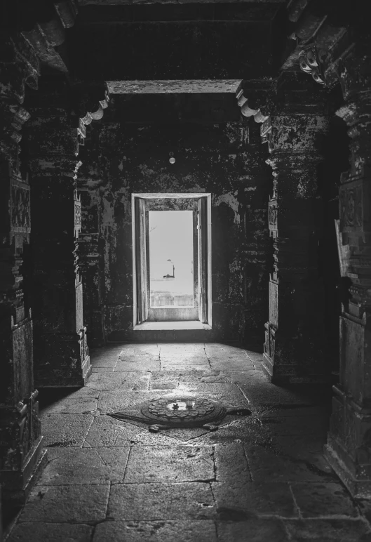 a light coming through a small window into a room with pillars