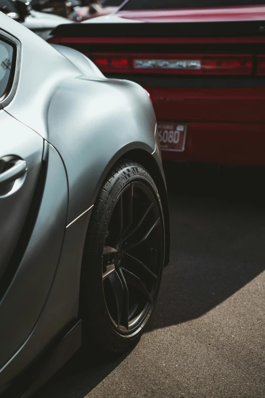 close up of silver sports car with red classic car in background