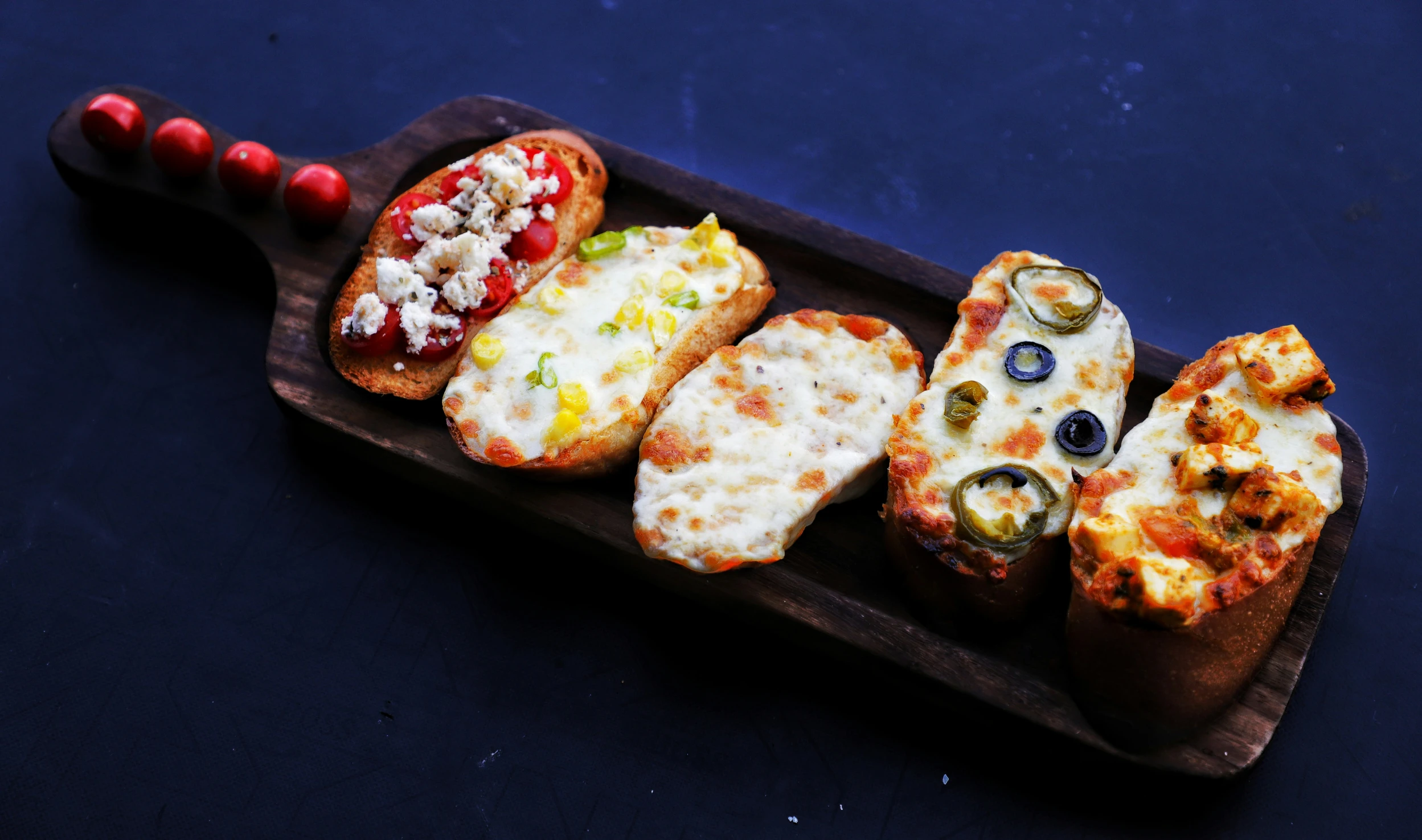 a wooden board holding four different pizzas