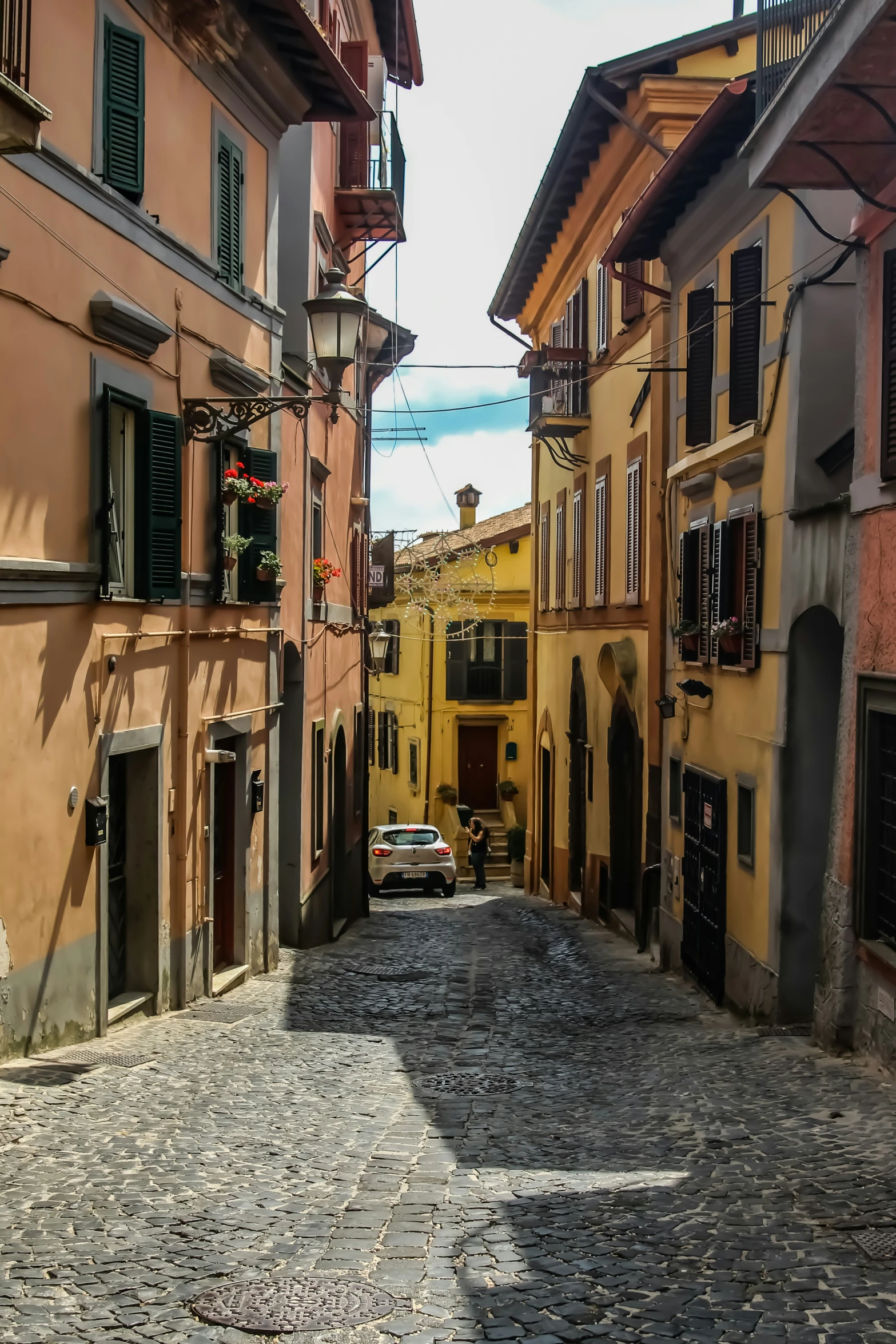 an alleyway leading to several buildings and a car parked