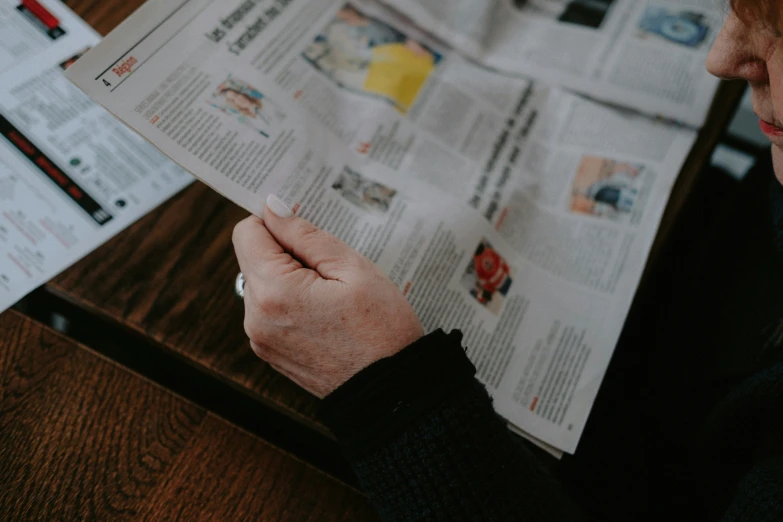 person sitting down reading the paper next to their phone