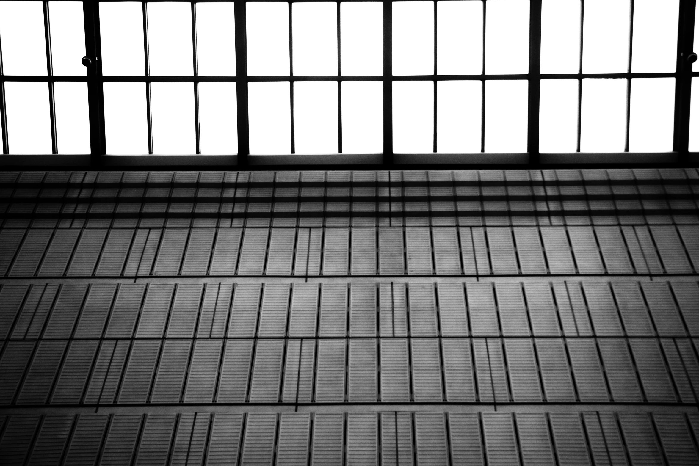 a black and white image of a man riding a skateboard down an indoor ramp