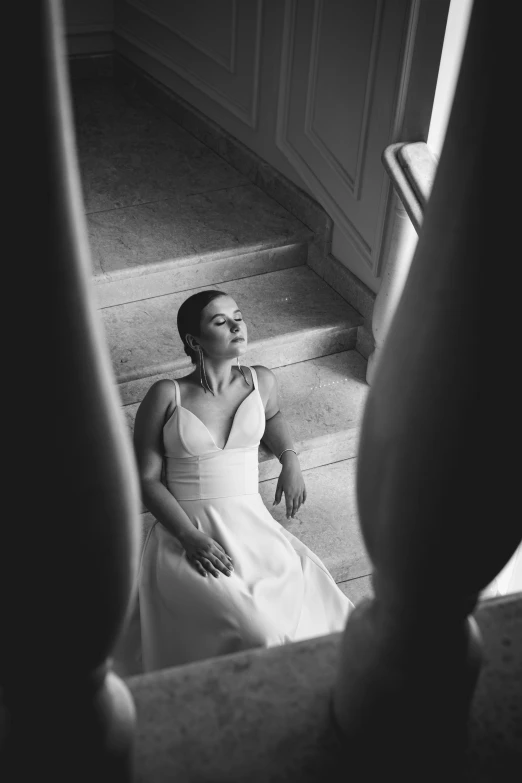 black and white pograph of woman sitting on stairs