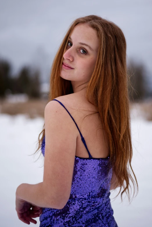 a woman in purple dress walking through the snow