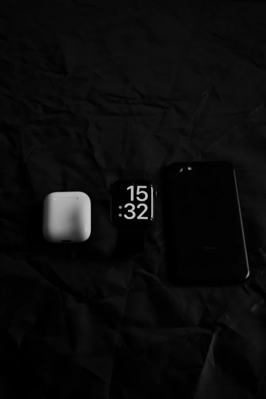 an alarm clock and two pieces of ipod on black fabric