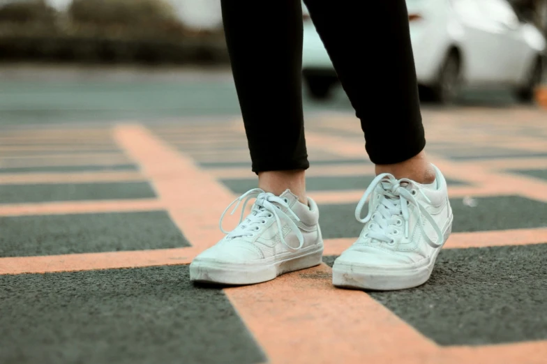 a woman with white tennis shoes standing on the street