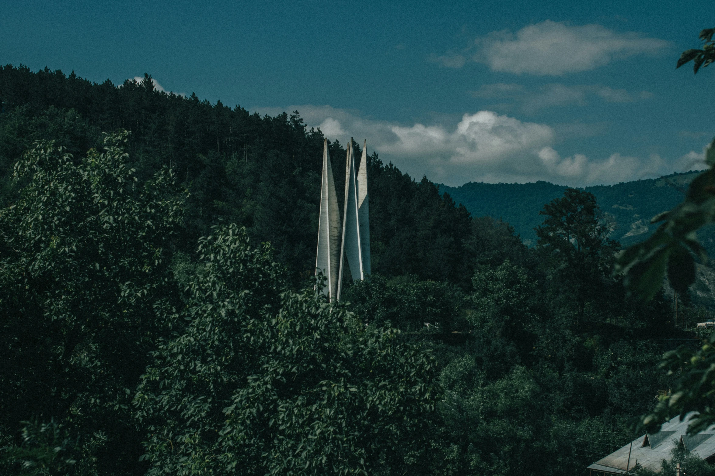 the mountain and sky have green trees in it