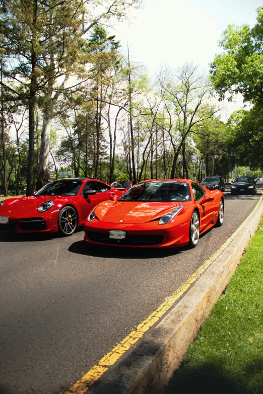 a couple of red sports cars driving down a street