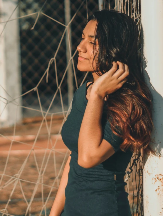 a woman leaning on the wall near a net