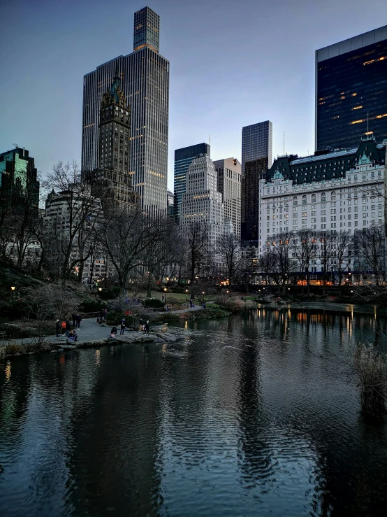 the city lights shine brightly over the lake in the park