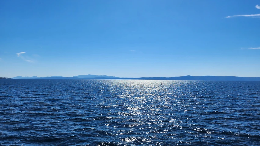 the sun shining brightly on the water under a blue sky