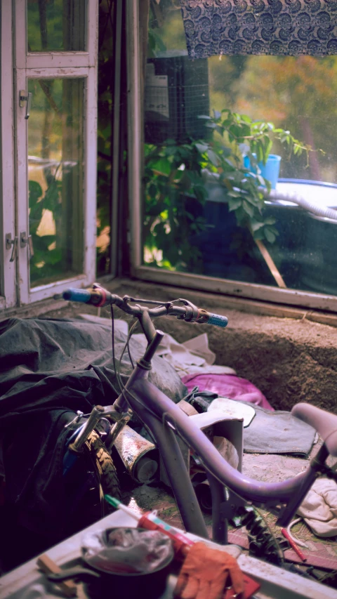 a purple bicycle parked next to a window and trash on the ground