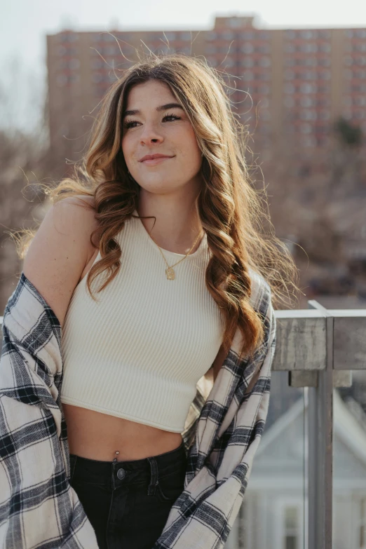 a beautiful woman standing on a balcony wearing plaid clothes