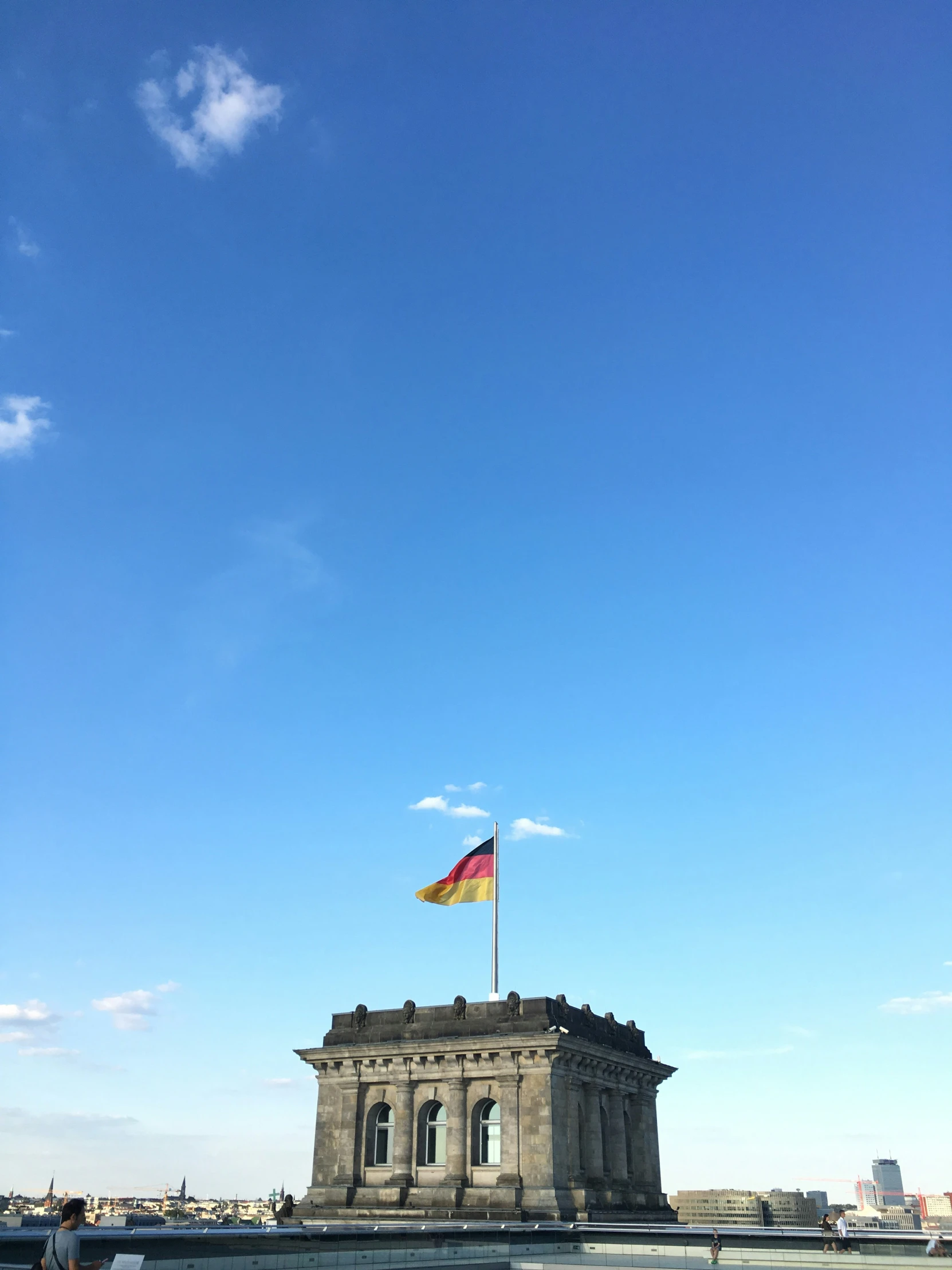 a tall flag on top of a building near a fence