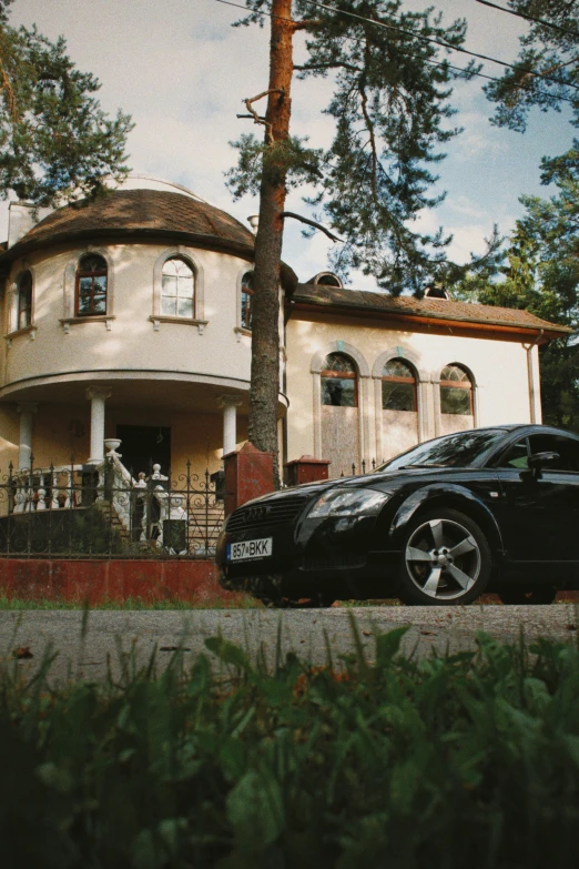 a luxury house with large driveway area and a black car parked in front