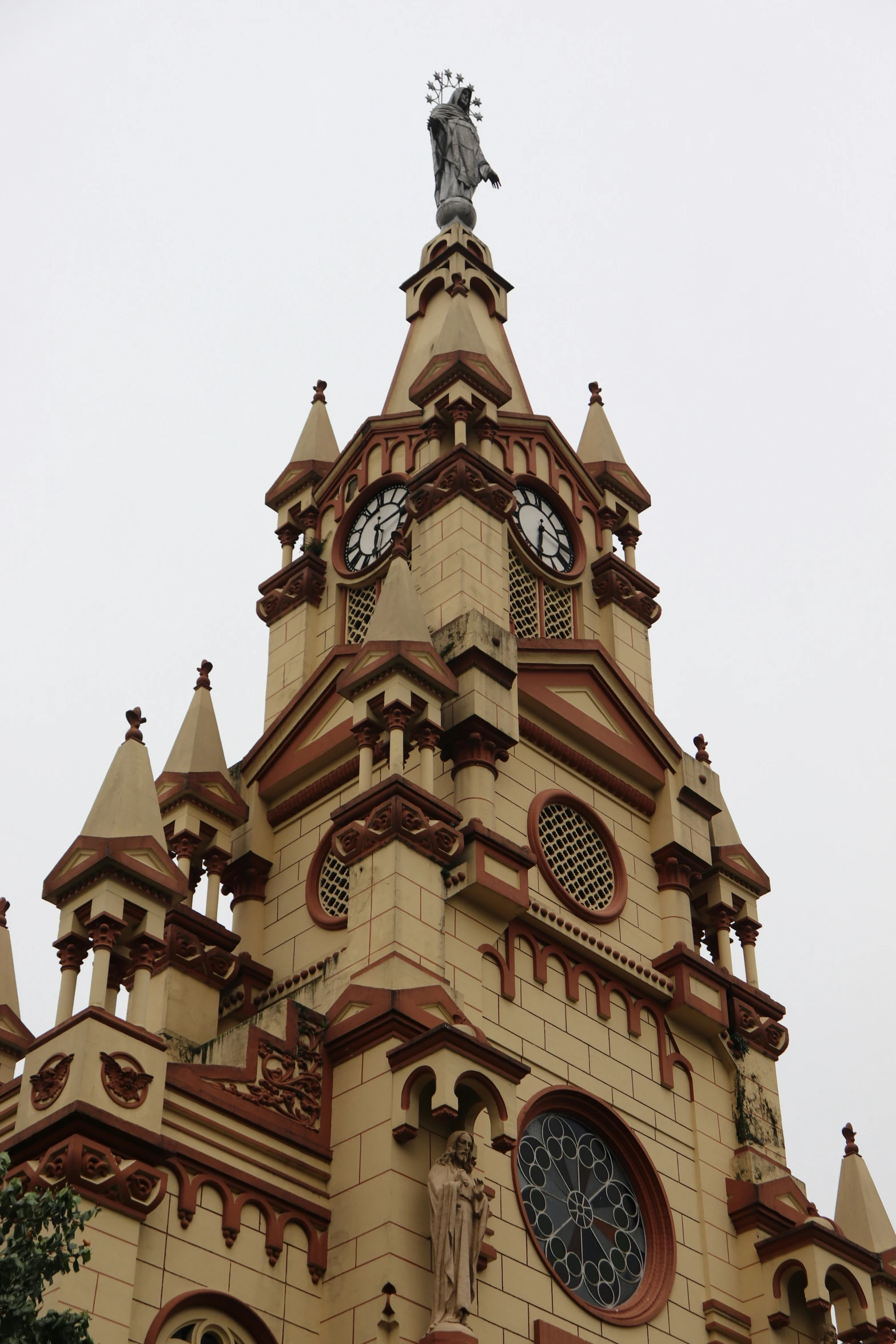 a fancy brown and tan church tower with a statue atop